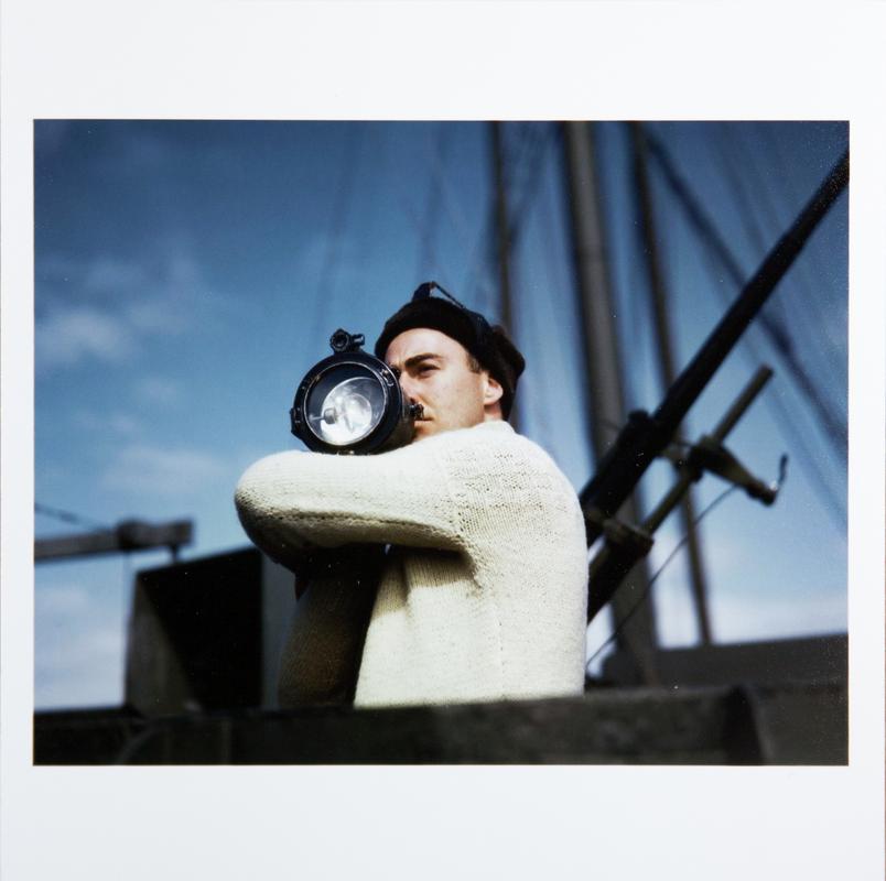 Crewman signals another ship of an Allied convoy across the Atlantic from the U.S. to England