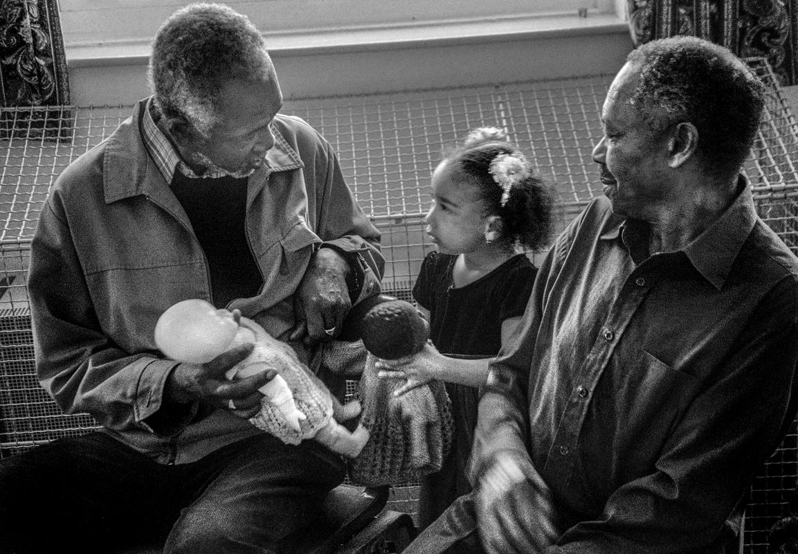 GB. WALES. Cardiff. Butetown - once know as 'Tiger Bay'. Carl Alexis and granddaughter in St Paul's, Loudoun Square. 2003.