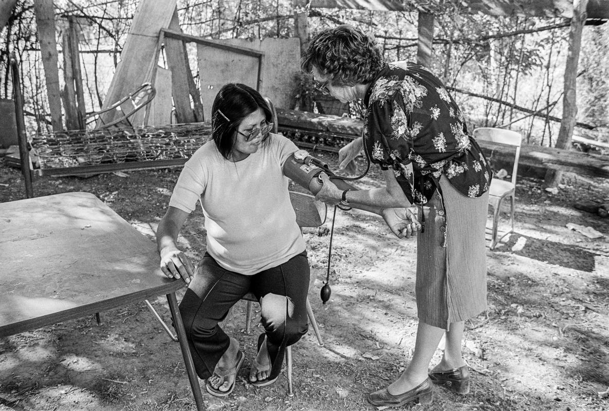 USA. ARIZONA. Doctor from Phoenix checking blood pressure of Apache woman on the reservation. Done in the open as they do not like strangers coming into their houses. 1980.