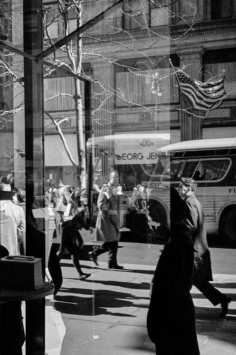 USA. NEW YORK. Manhattan. New Yorkers and the American flag. Reflections in a window. 1962