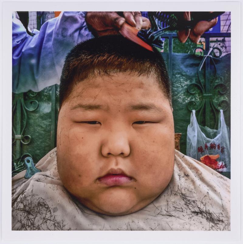 A boy gets a haircut in the street. Dalian, China