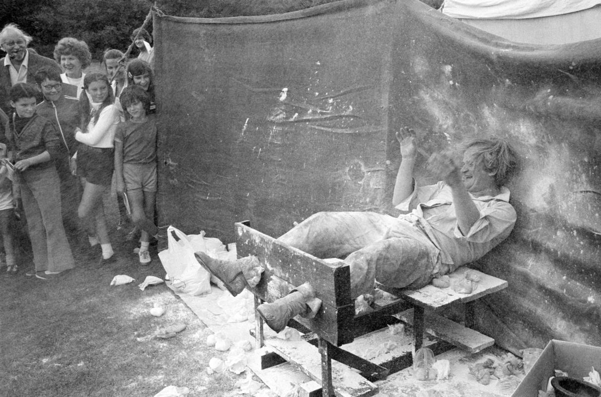 GB. WALES. Penarth. Side show (man in stocks having flour bags thrown at him) at Donkey Derby fete. 1973