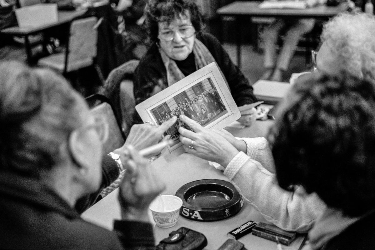 GB. WALES. Cardiff. Butetown (once called Tiger Bay). Winnie Salsbury (left) and friends reminiscing over an old photo at Butetown Community Centre. 1999