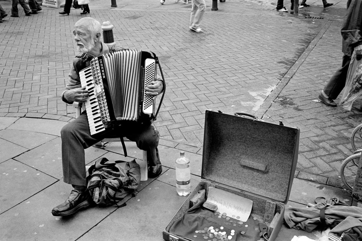 GB. WALES. Newport. Accordian, Busker playing music in the main street.  2008