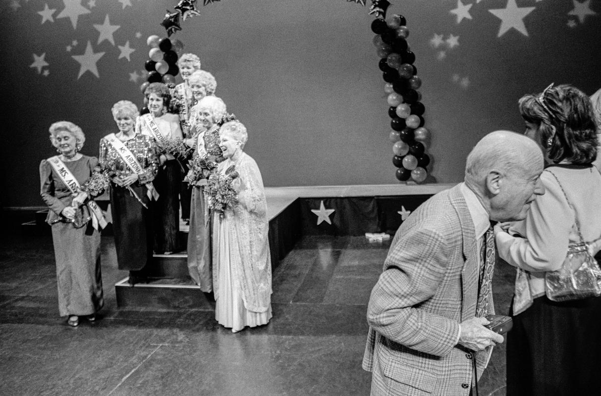 USA. ARIZONA. Sun City Ms Senior Pageant. The Ms competition is not only about beauty but poise and talent. A fan wanders by with his camera at the ready. The pageant is held at the Sun Dome Centre for the performing Arts. 1997.